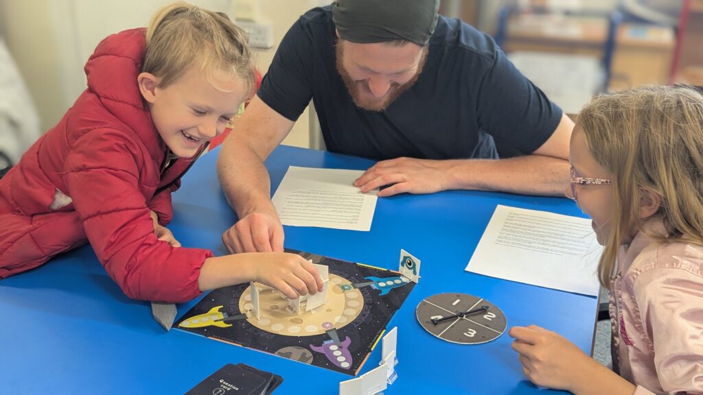 A young family of dad, son and daughter, playing Race to Your Rocket and laughing.