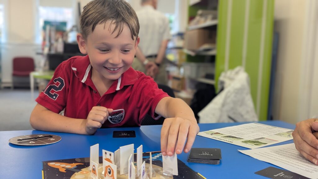 A laughing, smiling young boy playing Race to Your Rocket with his brother
