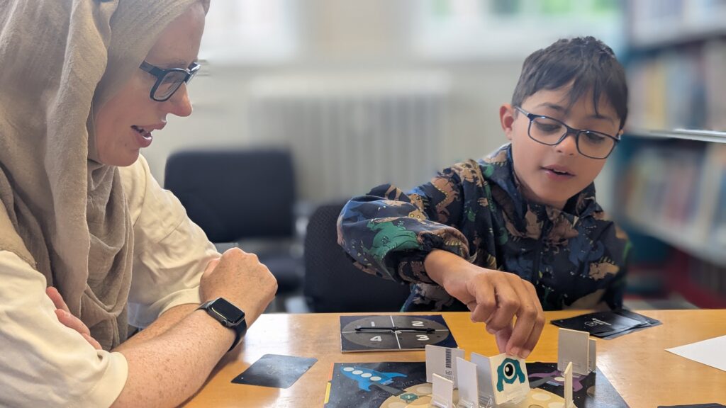 A 10 year old boy in adinosaur jacket, playing Race to Your Rocket with his mum.